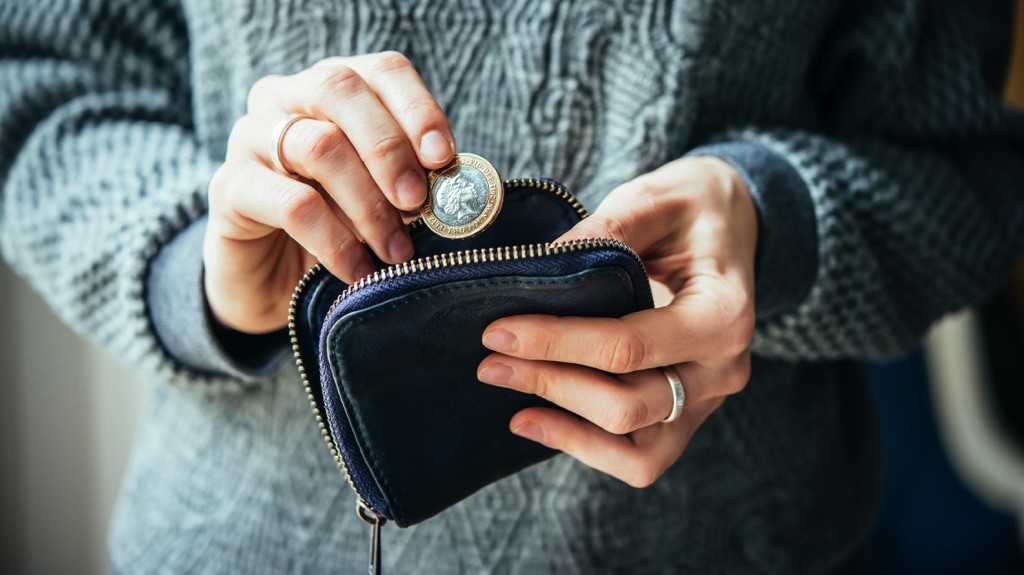Persona sacando solo una moneda de su billetera